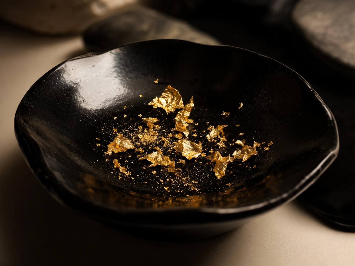 Food-grade 24K edible gold flakes and fine dust in a black-lacquer artisan dish